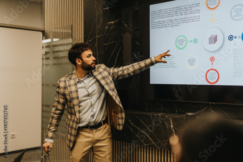 A business person presents late at night with a digital screen, using visuals to explain data. The setting indicates a dedicated and focused work environment, showcasing commitment and productivity.