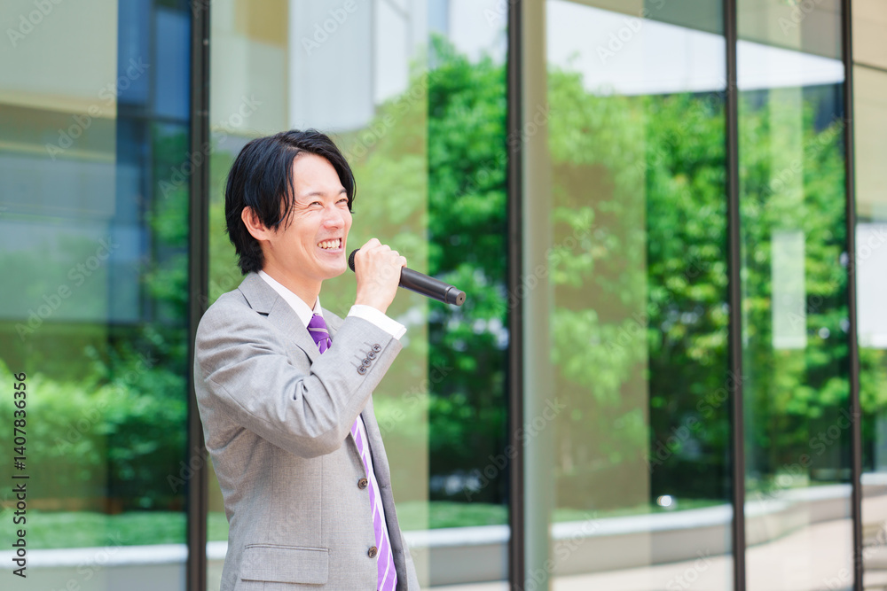 Fototapeta premium マイクを使って街なかで演説をするスーツを着た男性