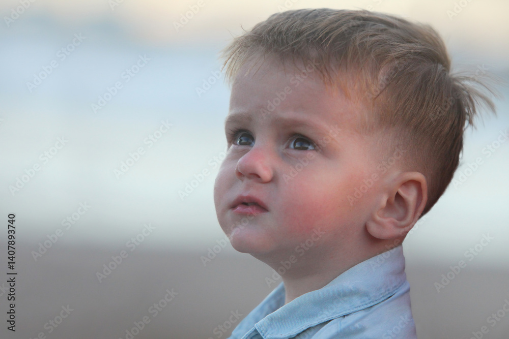 closeup portrait of a cute serious little toddler boy outdoors at dusk with ocean in background closeup portrait of a cute serious little toddler boy outdoors at dusk with ocean in background