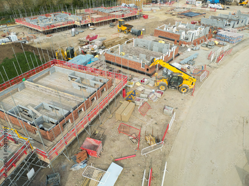Low level aerial view of a British housing development site in the east of the country. Showing partially built private and smaller, affordable homes. Located in rural Essex.