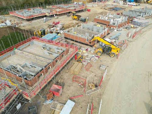 Low level aerial view of a British housing development site in the east of the country. Showing partially built private and smaller, affordable homes. Located in rural Essex.