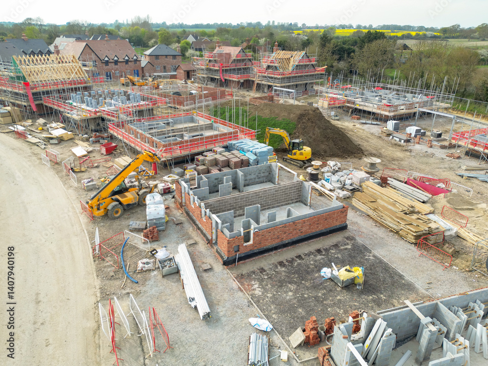 Low level aerial view of a British housing development site in the east of the country. Showing partially built private and smaller, affordable homes. Located in rural Essex.
