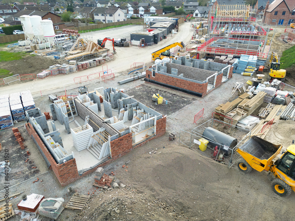 Low level aerial view of a British housing development site in the east of the country. Showing partially built private and smaller, affordable homes. Located in rural Essex.