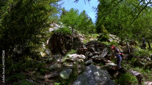 Solo female trekker hikes steep rocky trail in alpine forest