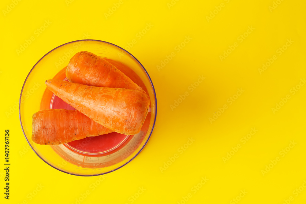 Kitchen scale with bowl of fresh carrots on yellow background, top view. Space for text