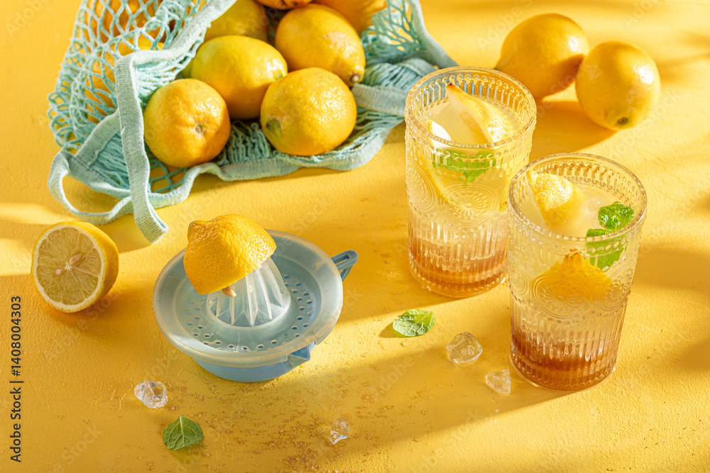 Sour lemonade with ice on yellow wooden table.