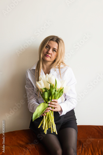 A woman holds white tulips in her hands