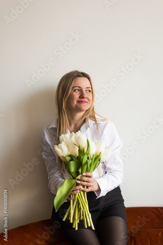 A woman holds white tulips in her hands