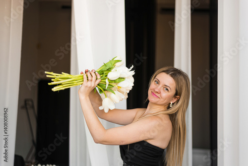 A woman holds white tulips in her hands