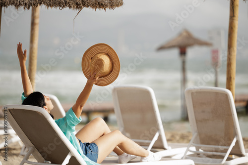 Woman relaxing on a beach lounger. Young woman enjoying a summer day in a hammock on the hotel's private beach.
