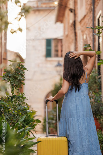 A woman walking through the city streets with her suitcase on her way to the airport to begin her summer vacation.
