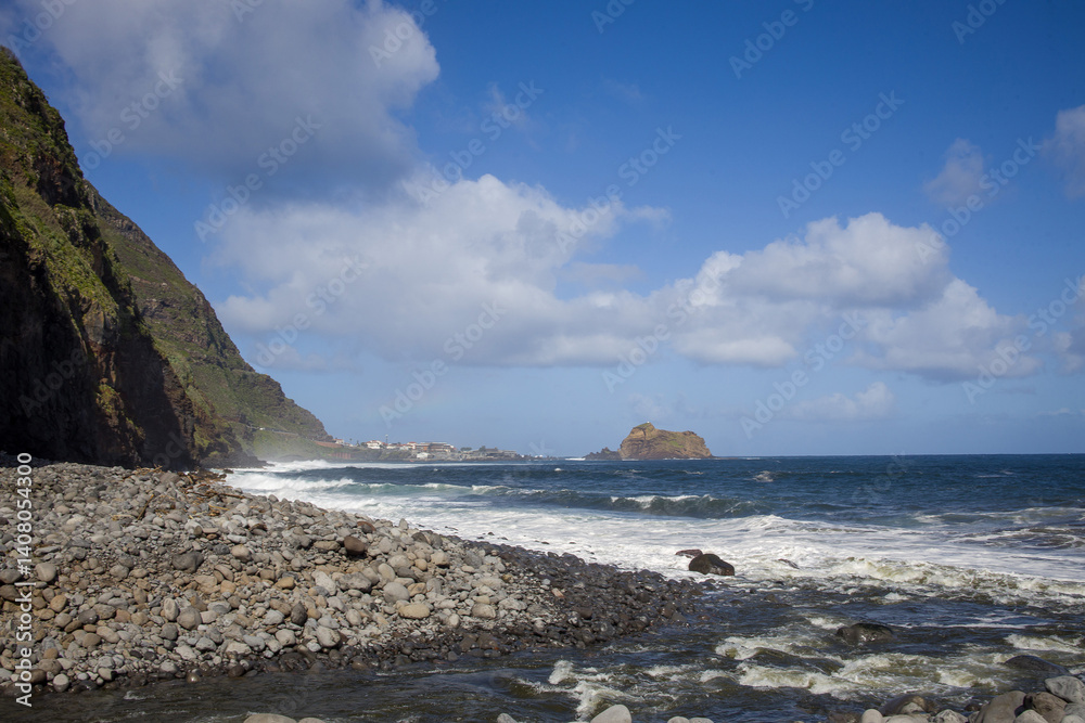 Coastal view of Madeira showcasing waves, rocky shores, and cliffs under a vibrant blue sky