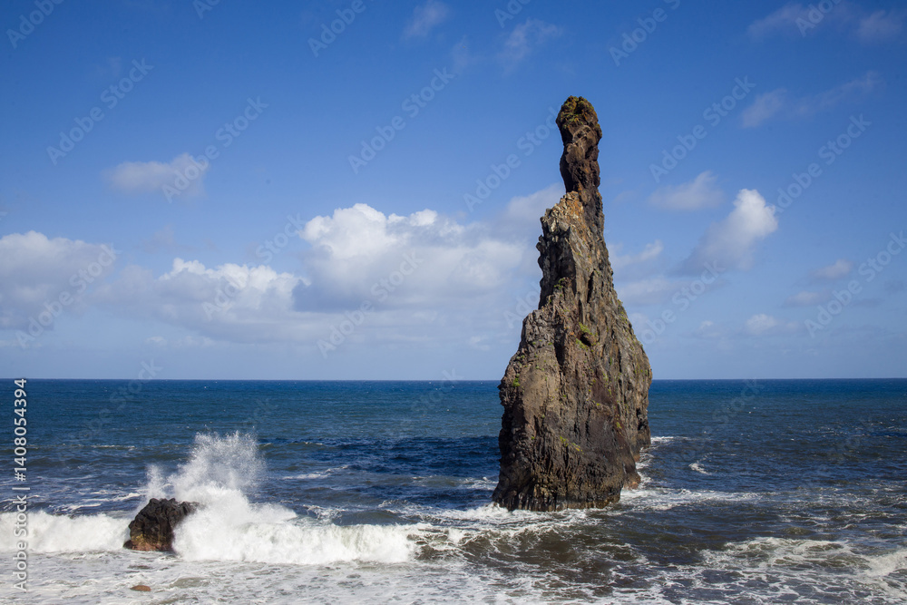 Ilheus da Ribeira, Madeira. Dramatic rock formations rise from the sea. Coastal landscape with waves and a blue sky.
