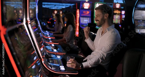 Young Man Wins at Casino Slot Machine and Celebrates with a Drink