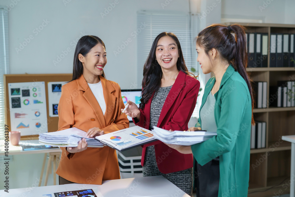 Fototapeta premium Group of smiling asian businesswomen discussing financial charts and analyzing sales data in modern office