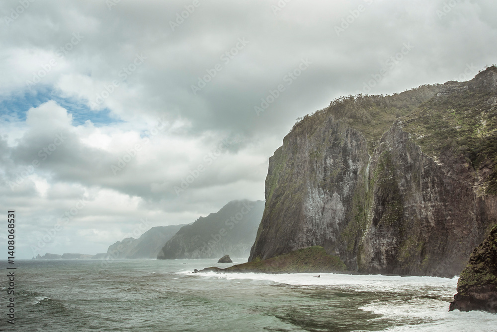 Fototapeta premium Furna do Porto da Cruz (Praia e Caís), Madeira Island, Portugal: Dramatic cliffs meet the ocean under a cloudy sky