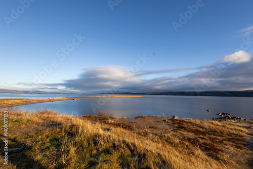 The Norwegian landscape unfolds in its full beauty, with towering mountains perfectly mirrored in the calm waters of a fjord. The natural mirror of the water captures every detail of the surroundings,