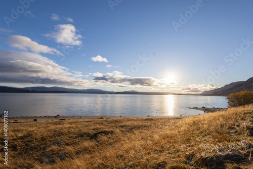 The Norwegian landscape unfolds in its full beauty, with towering mountains perfectly mirrored in the calm waters of a fjord. The natural mirror of the water captures every detail of the surroundings,