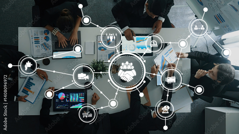 A dynamic overhead view of a collaborative business meeting showcasing professionals engaged in data analysis and strategy discussion using modern technology in a stylish office environment. Amity