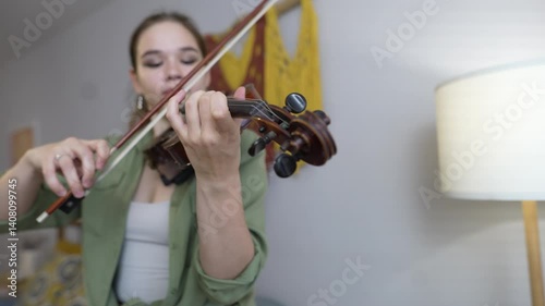 A woman hand moves along the neck of the violin, pinching the strings and chords. Playing the violin at home, close-up