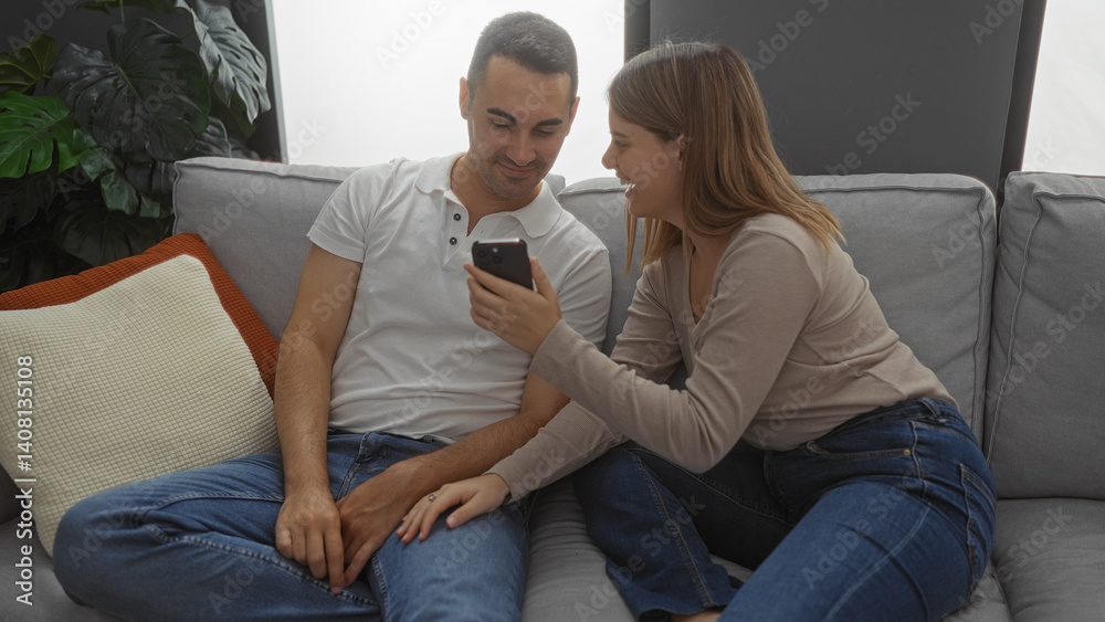 Couple relaxing in a cozy living room, woman showing man something on phone, love and happiness evident in their interaction, surrounded by homey decor, both enjoying a shared moment. Couple relaxing in a cozy living room, woman showing man something on phone, love and happiness evident in their interaction, surrounded by homey decor, both enjoying a shared moment.