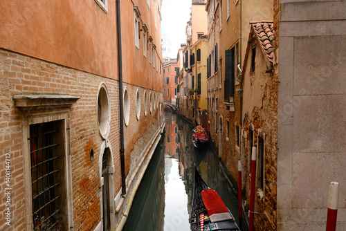 Fototapeta Naklejka Na Ścianę i Meble -  Typical narrow streets and canals between Colorful and shabby houses in Venice, Italy. Historical architecture in Venice, parked boats on the canals.