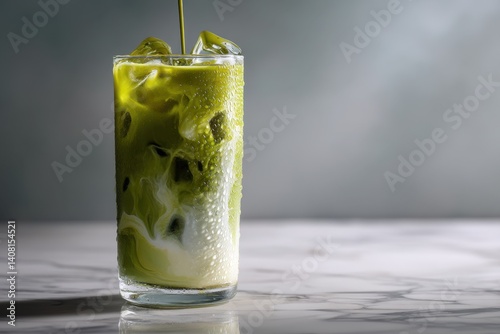 A studio shot showcases a glass of iced matcha latte with swirling milk, condensation, and soft lighting against a reflective marble surface.