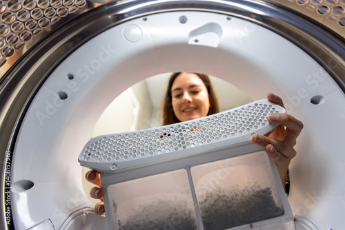 Woman cleaning dust and dirt from the clothes dryer filter. Cleaning out after drying the clothes.