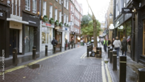 Canvas Print Blurred street scene in london with defocused pedestrians walking in seven dials amidst bokeh lights on a rainy winter day, capturing the essence of urban england