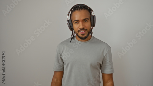 Obraz na płótnie Young man with braided hair and headphones stands confidently against a plain white background, embodying an engaging and contemporary look. w salonie