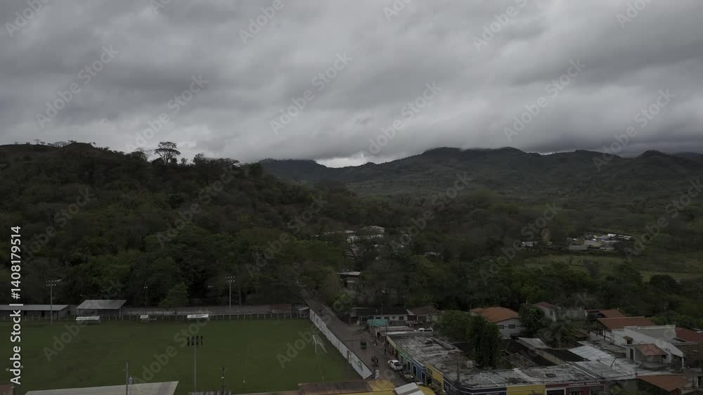 Drone rises up in front of football pitch, soccer field, in dense forest on a cloudy afternoon Drone rises up in front of football pitch, soccer field, in dense forest on a cloudy afternoon