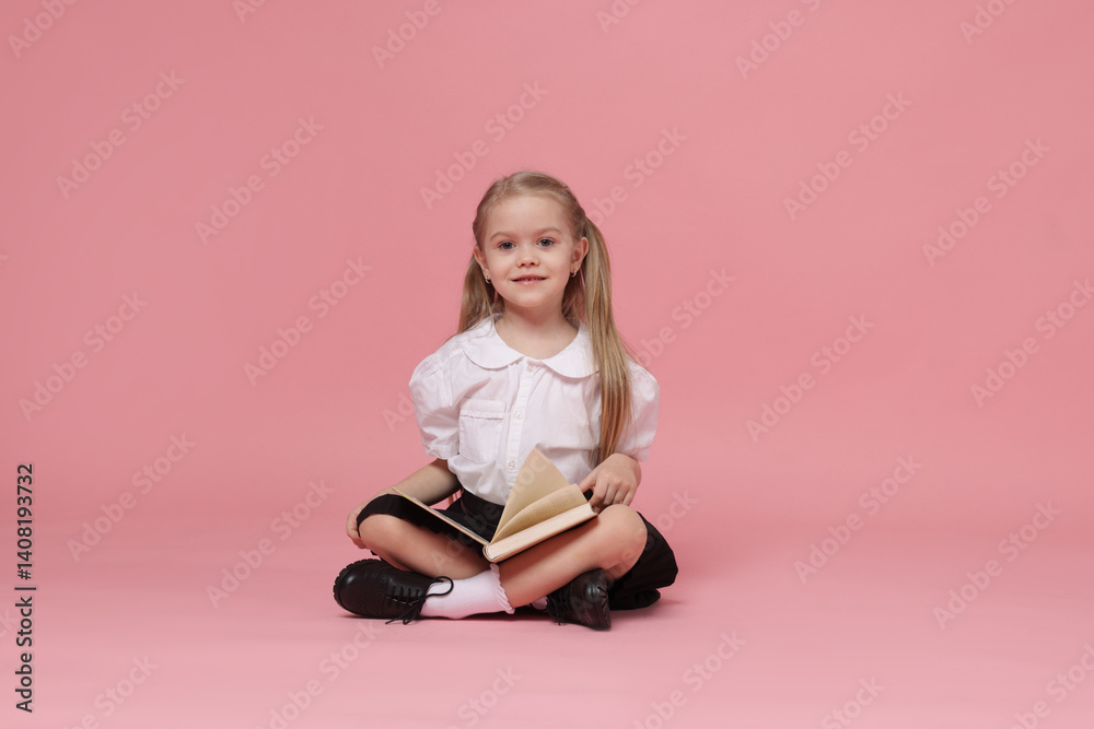 Cute schoolgirl with book on pink background Cute schoolgirl with book on pink background
