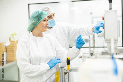 A woman operates a control panel while a colleague observes, highlighting precision and teamwork in pharmaceutical technology.