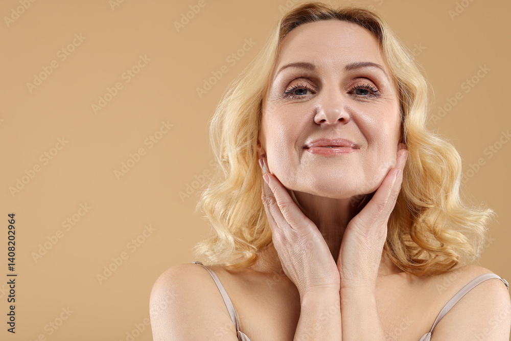 Beautiful middle aged woman on beige background. Space for text Beautiful middle aged woman on beige background. Space for text