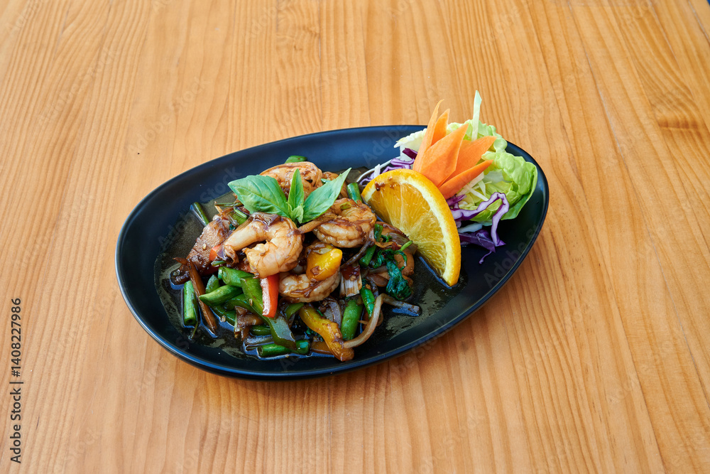 A plate of food with shrimp, carrots, and greens. The plate is black and the food is on a wooden table