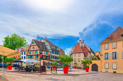 Fototapeta Naklejka Na Ścianę i Meble -  Old houses half-timbered style colorful facade medieval buildings multicolored walls and street restaurants on small square in old town Colmar city historic centre, Alsace Grand Est region, France