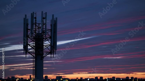 Telecommunication tower stands tall against colorful sunset sky. Metal structure supports 5G antennas. Modern tech equipment transmits signals. Wireless communication systems operate at high
