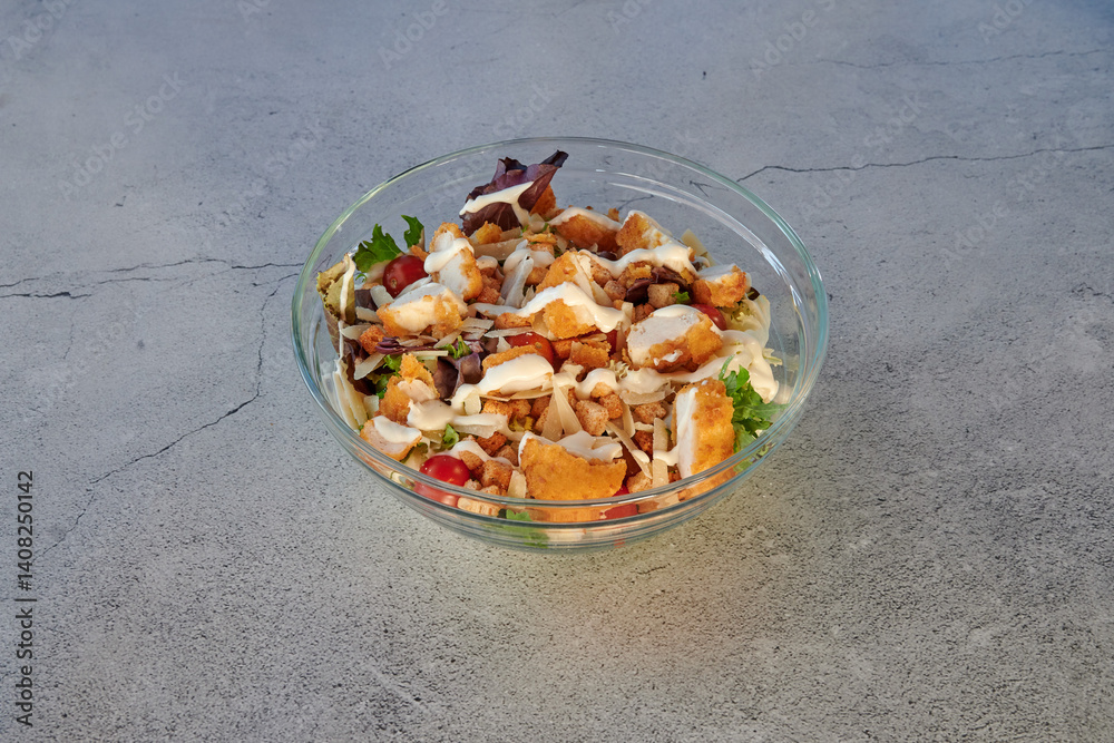 A plate of food with chicken, bacon, and lettuce. The plate is white and the food is on a black surface