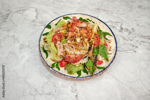 Obraz na płótnie A salad with lettuce, tomatoes, and chicken on a white plate. The plate is on a marble counter w salonie