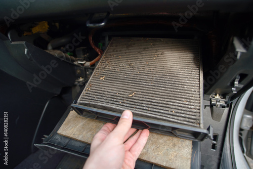 Obraz na płótnie Removing contaminated vehicle cabin filter during inspection to improve air conditioning system performance and eliminate allergens from circulating. Hand extracting heavily used cabin filter w salonie