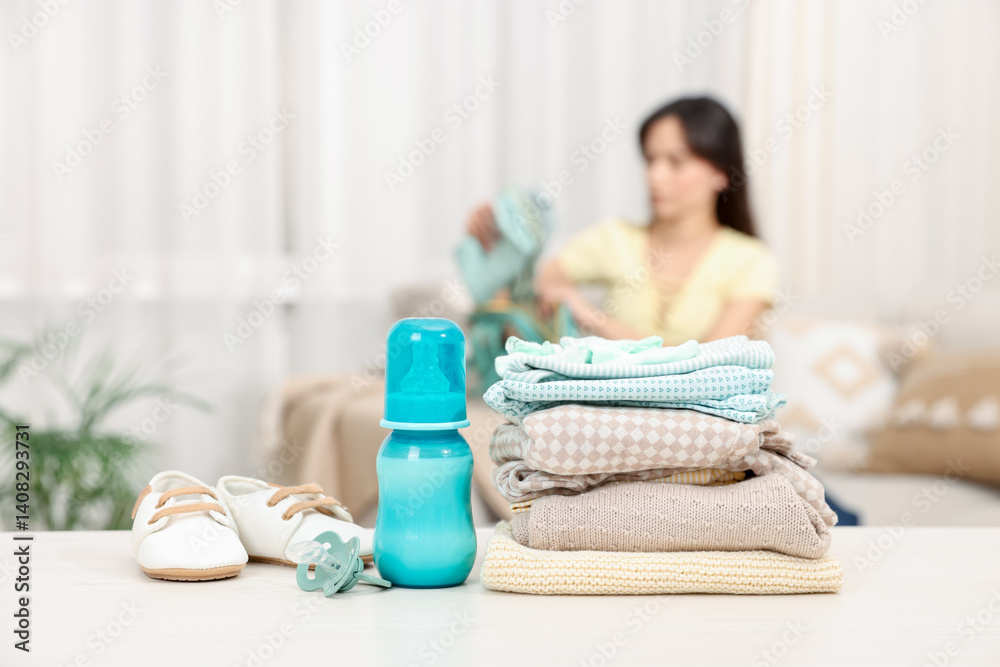 Baby's stuff on white table and mother packing bag, selective focus