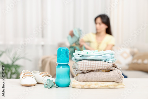 Baby's stuff on white table and mother packing bag, selective focus