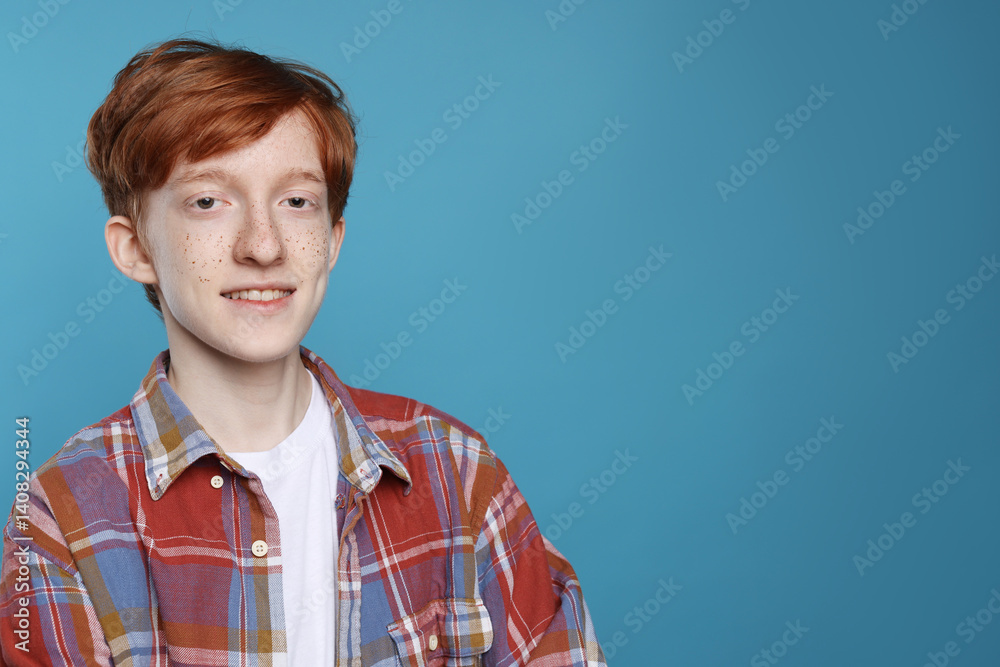 Smiling teenage boy with freckles on light blue background. Space for text Smiling teenage boy with freckles on light blue background. Space for text