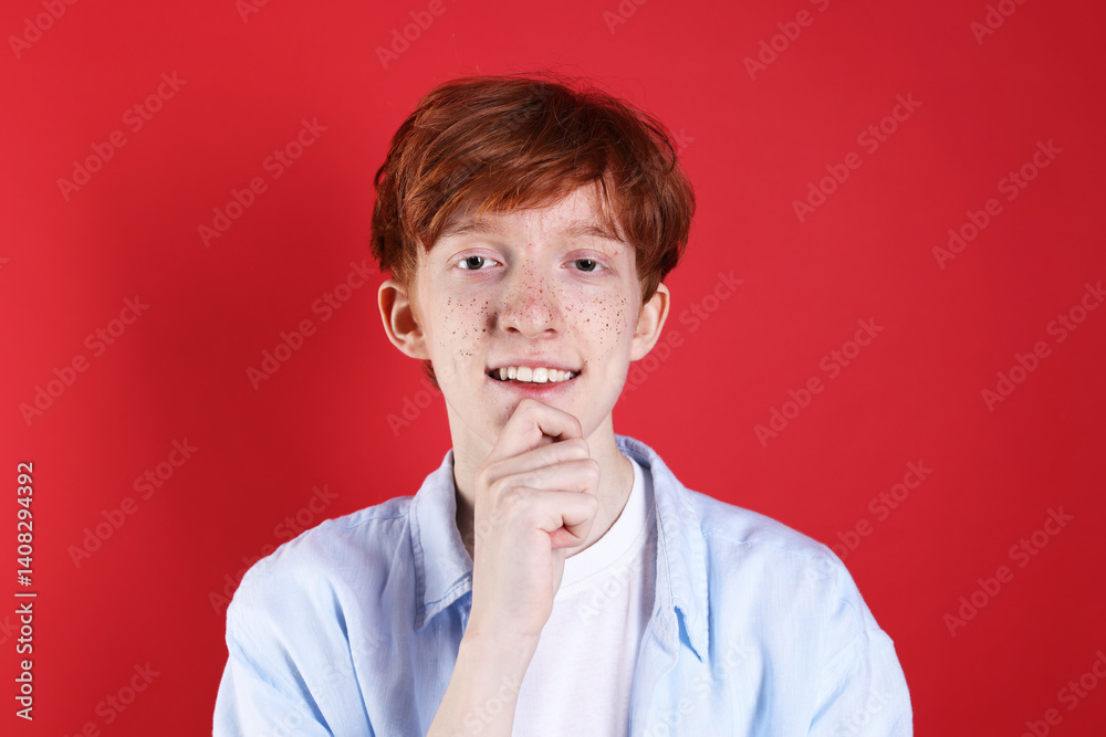 Smiling teenage boy with freckles on red background Smiling teenage boy with freckles on red background