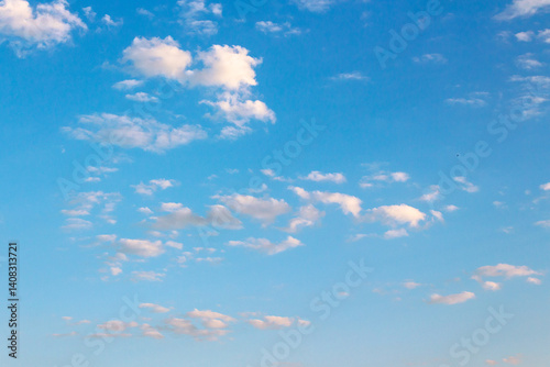 blue sky with many clouds on a sunny august morning. fluffy formations in bright weather. dynamic arrangement in the air. blue nature backdrop in morning light. warm forecast background