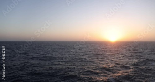 11 second 4k video clip of bright yellow sun setting on ocean horizon captured from balcony of moving cruise ship 