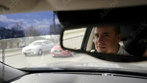 Wallpaper Mural Confident businessman navigating urban streets, reflection showing professional demeanor while driving through city during sunny daytime Torontodigital.ca