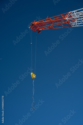Construction crane jib with hook hanging down on blue sky background
