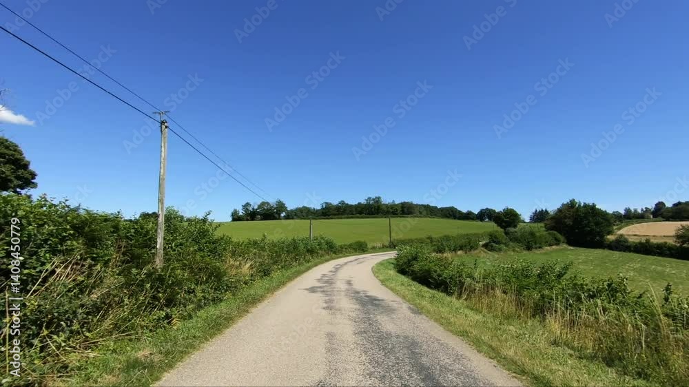 The rural path that winds through the green nature in Europe, in France, in Burgundy, in Nievre, towards Chateau Chinon, in summer, on a sunny day. 