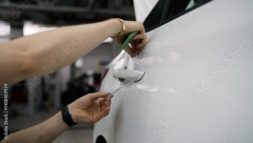 Photos Professional car detailer applying protective film on white car door handle